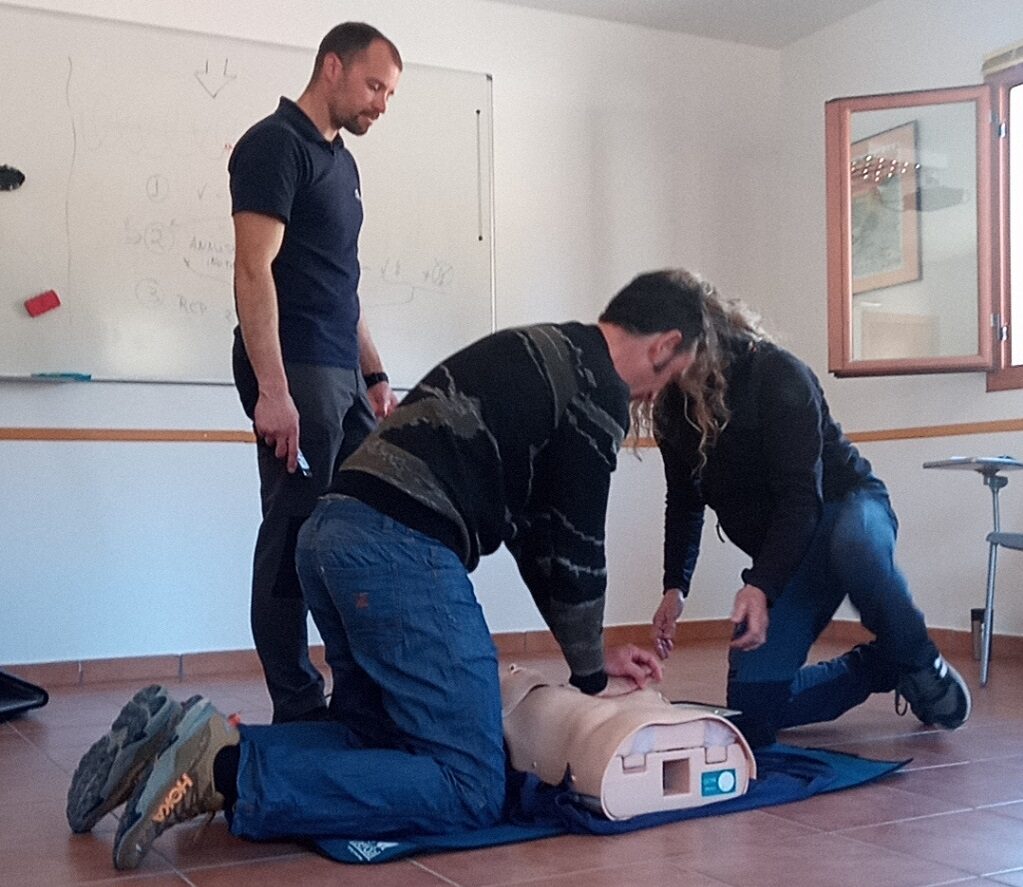Instructores y alumnos realizando maniobras de RCP básica con maniquí en aula de formación. 