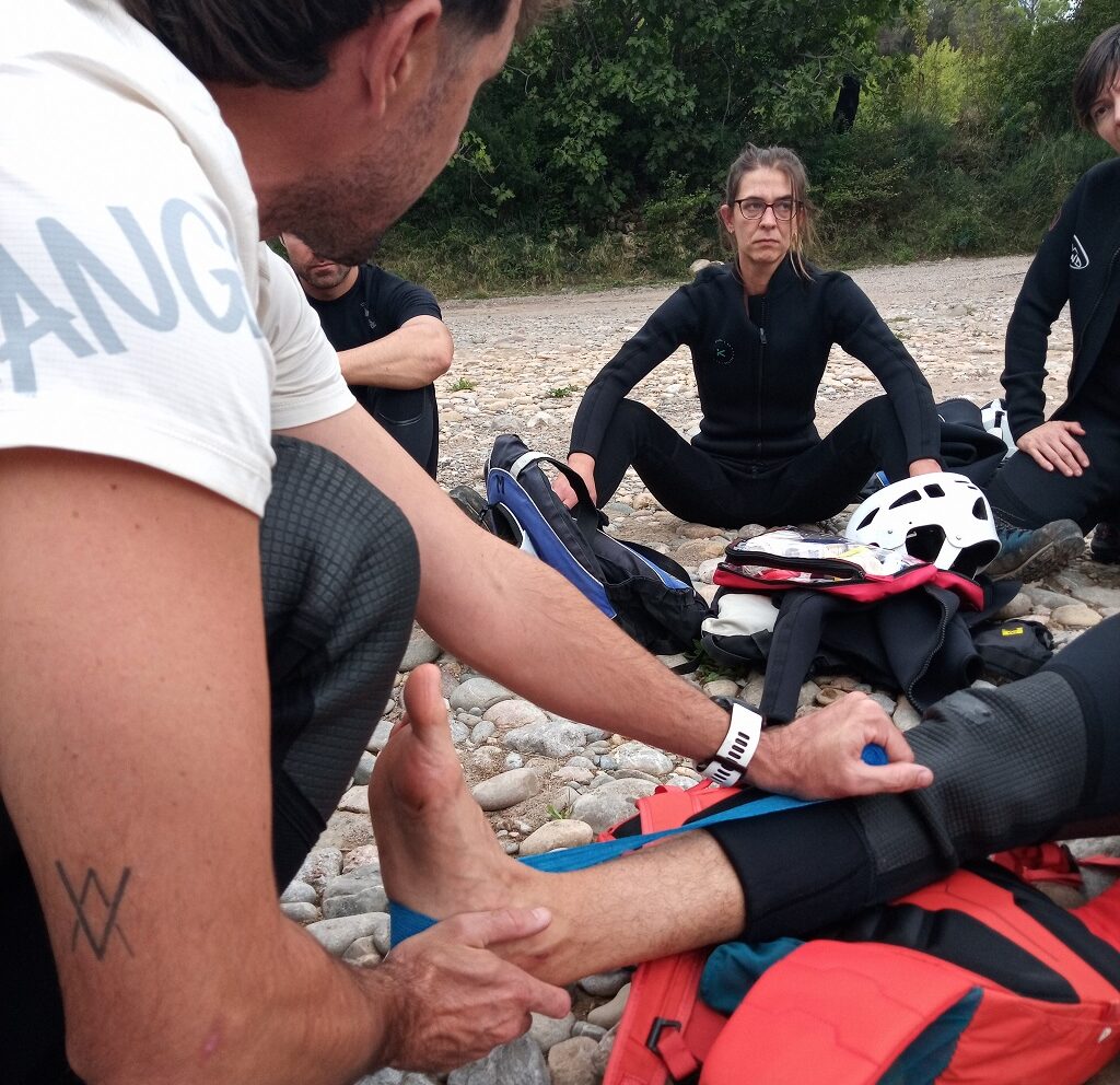 Práctica de inmovilización de tobillo y pierna en terreno pedregoso durante el curso de primeros auxilios.